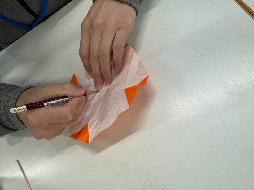 折り紙に鉛筆で線を書いている